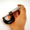 Close-up of a General Tools 102 Graduation Micrometer in someone's hand, showcasing its clear graduation scale and ergonomic design.